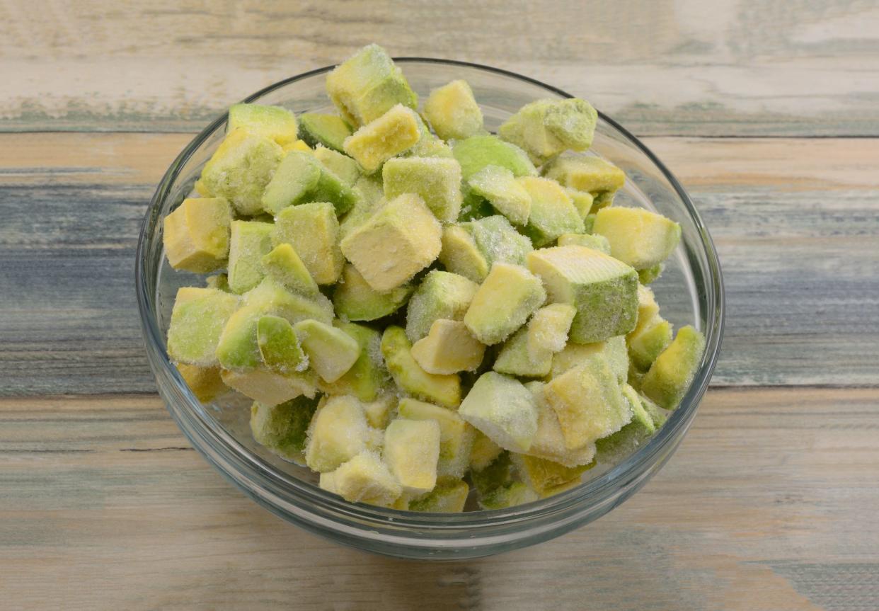 Frozen avocado chunks thawing in glass ingredient bowl on table