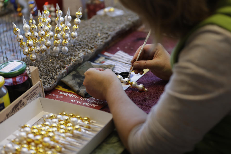 In this picture taken on Wednesday, Nov. 28, 2018, a traditional worker hand paints small blown glass beads for Christmas decorations in the village of Ponikla, Czech Republic. The small family business in a mountainous village in northern Czech Republic is the last place in the world where traditional Christmas decorations are made from glass beads blown and painted by hand. (AP Photo/Petr David Josek)