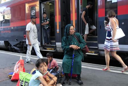 Travellers sit on a platform as they wait for a train to Austria at the railway station in Budapest, Hungary, August 31, 2015. REUTERS/Bernadett Szabo