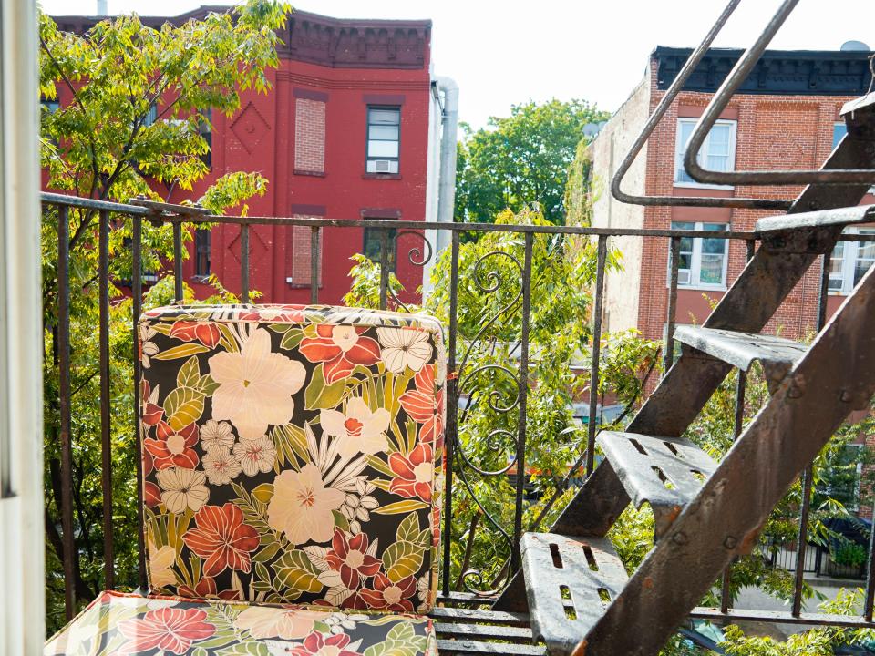 The author's fire escape in her Brooklyn apartment has flower couch cushions on the left and stairs on the right