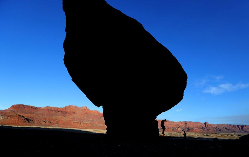 Visitors climb rock formations near the Colorado River at Lee's Ferry.