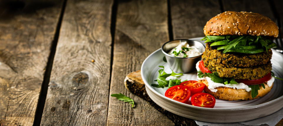 Vegan zucchini burger and ingredients on rustic wood background, copy space