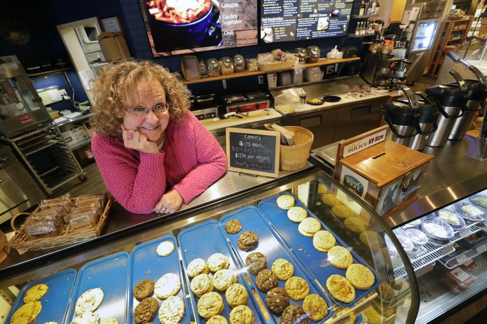 Chanda Anderson stands behind a display of Caramel Crisp Corner's famous cookies March 15, 2022, at the cafe, 200 City Center D, in Oshkosh, Wis. The business includes a book store, toy store, gift shop and a cafe with a full menu.