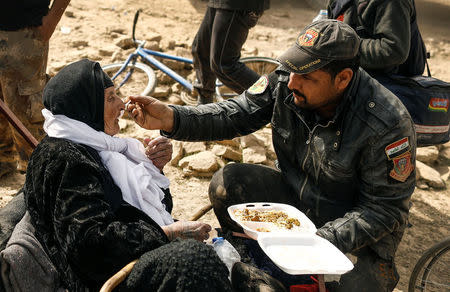 A special forces member feed a displaced Iraqi woman who just fled her home, as she waits to be transported while Iraqi forces battle with Islamic State militants in western Mosul, Iraq February 27, 2017. REUTERS/Zohra Bensemra