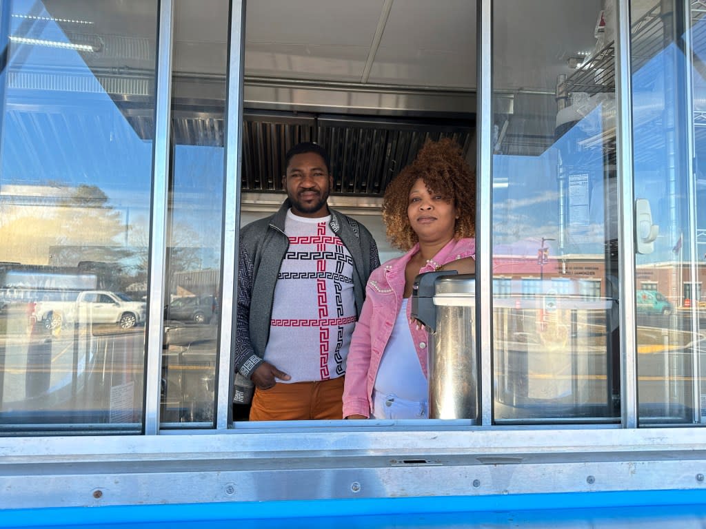 Theslet Benoir and Clemene Bastien stand at the window of their Eben-Ezer Haitian food truck in Parksley, Va., on Wednesday, Jan. 24, 2024. The married couple is suing the town in federal court over allegations that their food truck was forced to close. The couple also says a town councilman cut the mobile kitchen’s water line and screamed, “Go back to your own country!” (AP Photo/Ben Finley)