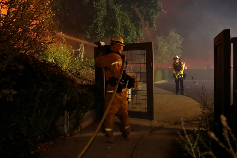 A firefighter hoses a hot spot while battling the Kincade fire at in Geyserville, California