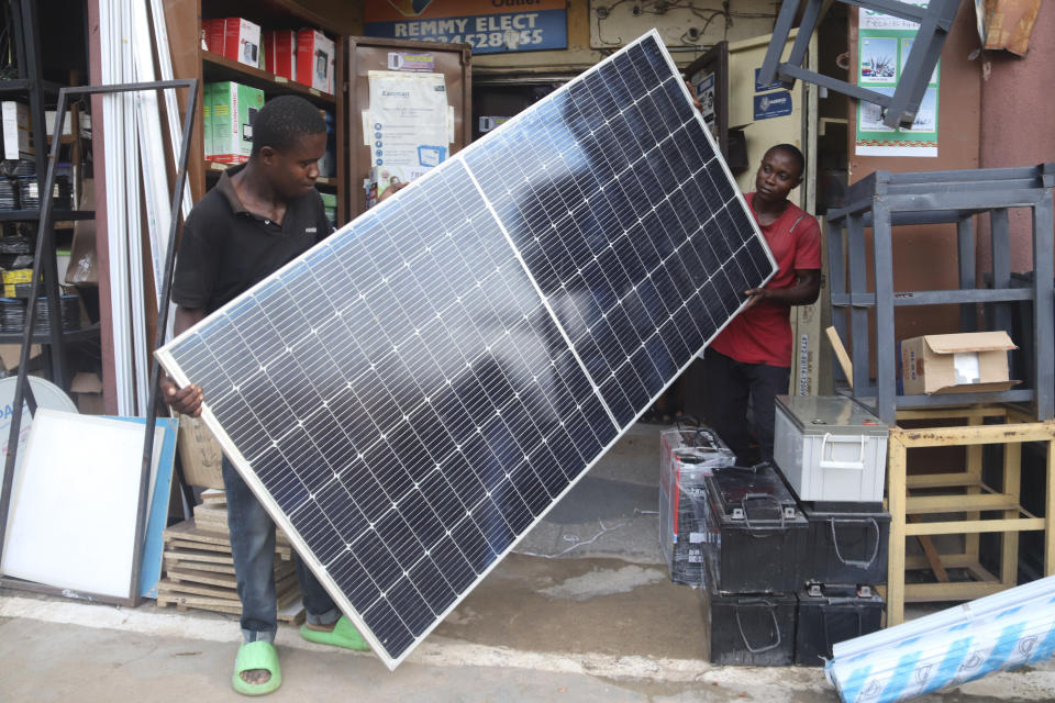 Men display a solar panel for sale at a shop in Abuja, Nigeria, Saturday June 17, 2023. Nigeria's removal of a subsidy that helped reduce the price of gasoline has increased costs for people already struggling with high inflation. But it also potentially accelerates progress toward reducing emissions in Africa's largest economy. (AP Photo/Olamikan Gbemiga)