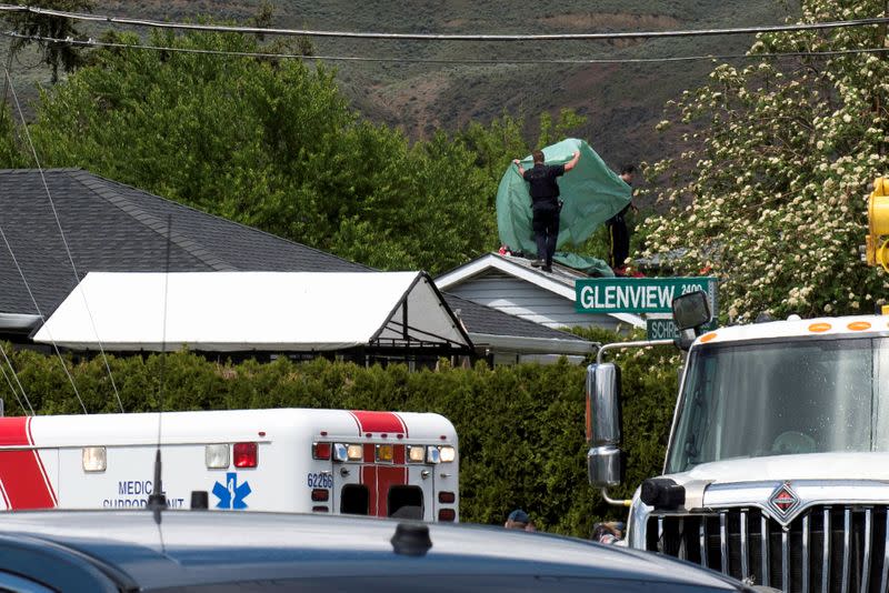 RCMP officers place a tarp over the roof of a house where a member of the Royal Canadian Air Force Snowbirds landed in Kamloops