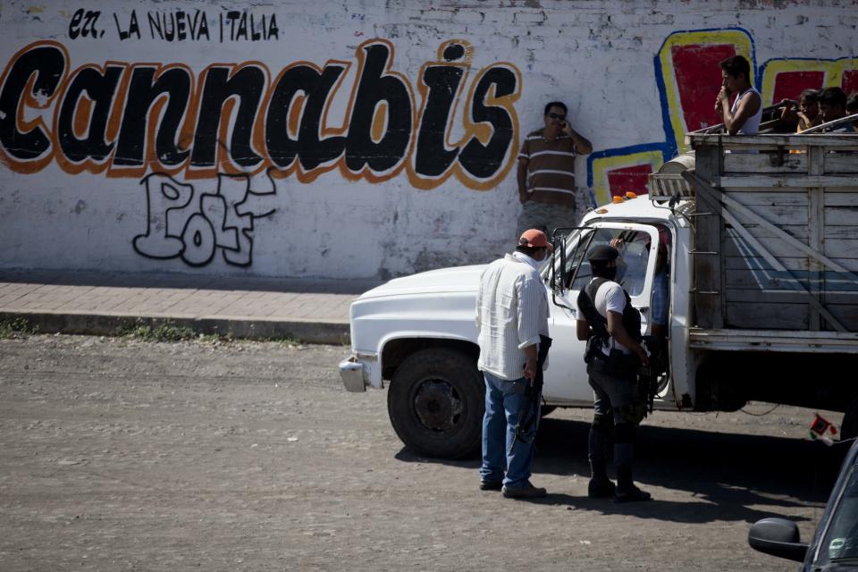 Men belonging to the Self-Defense Council of Michoacan, (CAM), inspect vehicles at a checkpoint in the entrance to the town of Nueva Italia, Mexico, Monday, Jan. 13, 2014. A day earlier the self-defenses encountered resistance as they tried to rid the town of the Knights Templar drug cartel while the government announced today that federal forces will take over security in a large swath of a western Mexico that has been hard hit by violence. (AP Photo/Eduardo Verdugo)