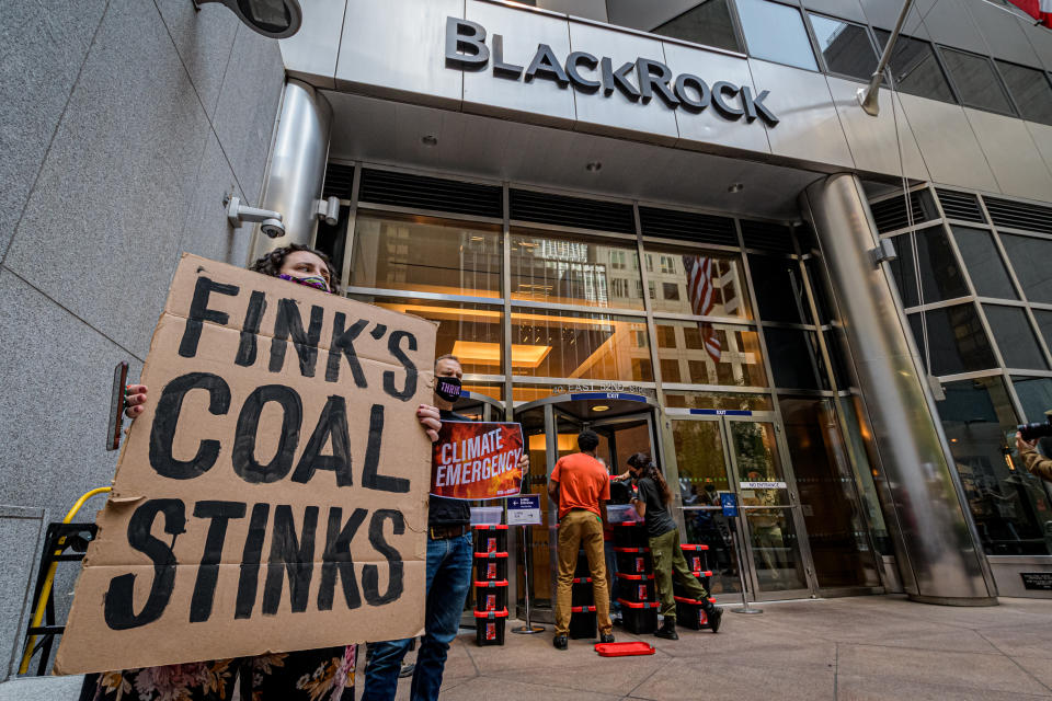 Participante visto sosteniendo un cartel contra el carbón en una protesta climática fuera de la sede de BlackRock.