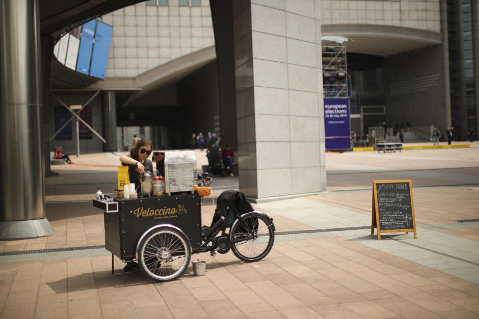 French coffee maker Noa waits for customer outside the European Parliament at the European quarter in Brussels, Thursday, May 23, 2019. Dutch and British voters were the first to have their say Thursday in elections for the European Parliament, starting four days of voting across the 28-nation bloc that pits supporters of deeper integration against populist euroskeptics who want more power for their national governments. (AP Photo/Francisco Seco)