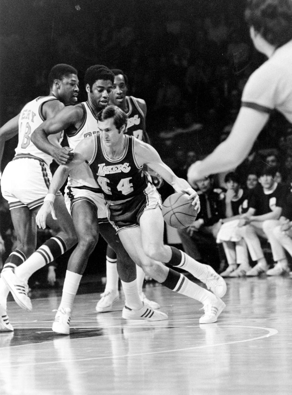 FILE - Los Angeles Lakers' Jerry West (44) drives around Milwaukee Bucks' Oscar Robertson and Curtis Perry during the NBA playoffs in Milwaukee, April 14, 1972. West used a pick set by Happy Hairston, background, before moving toward the basket. Lakers won 108-105. Jerry West, who was selected to the Basketball Hall of Fame three times in a storied career as a player and executive and whose silhouette is considered to be the basis of the NBA logo, died Wednesday morning, June 12, 2024, the Los Angeles Clippers announced. He was 86.(AP Photo/File)