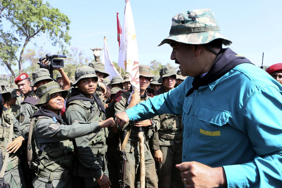 In this handout photo released by Miraflores Press Office, Venezuela's President Nicolas Maduro fist bumps with a cadet at the G/J José Laurencio Silva military training center in the state of Cojedes, Venezuela, Saturday, May 4, 2019. (Jhonn Zerpa/Miraflores Press Office via AP)