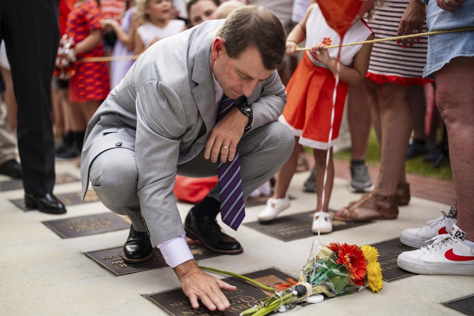 Clemson head coach Dabo Swinney stops to pay his respects to former Clemson player Diondre Overton while walking to the stadium before an NCAA college football game against Appalachian State, Saturday, Sept. 7, 2024, in Clemson, S.C. (AP Photo/Jacob Kupferman)