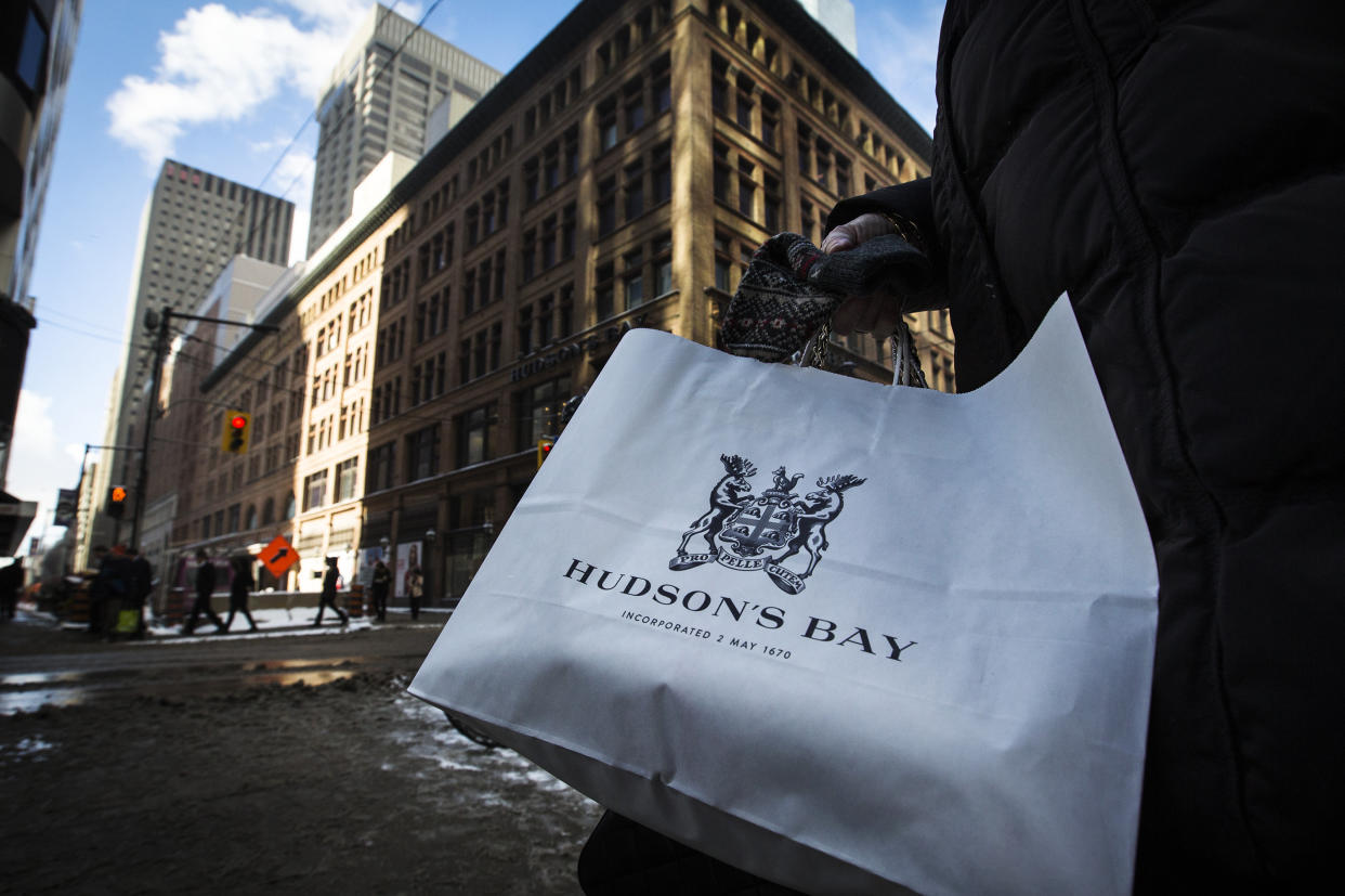 A woman holds a Hudson's Bay shopping bag in front of the Hudson's Bay Company (HBC) flagship department store in Toronto January 27, 2014.  Hudson's Bay Co said on Monday that it would sell its flagship downtown Toronto store and neighboring executive offices for C$650 million ($587.09 million) to Cadillac Fairview Corp and open a full-line Saks store in the leased-back space. The Canadian retailer, which completed its $2.4 billion purchase of U.S. luxury chain Saks Inc late last year, said it expects to open an approximately 150,000 square-foot, multi-level Saks in the fall of 2015, co-located with the current Hudson's Bay store.  REUTERS/Mark Blinch (CANADA - Tags: BUSINESS)