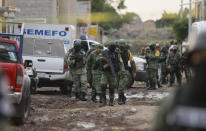 Members of the national guard walk near an unregistered drug rehabilitation center in Irapuato, Mexico, Wednesday, July 1, 2020, after gunmen burst into the facility and opened fire. More than 20 people were killed and several were wounded in the attack, authorities said. (AP Photo/Mario Armas)