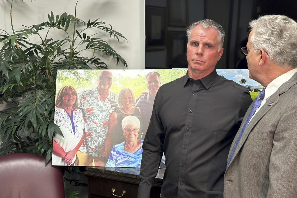 Bill Serge stands with his attorney Gary Lesser next to a photo on Thursday, Jan. 25, 2024, of his 85-year-old mother, Gloria Serge, who was killed in an alligator attack on Feb. 20, 2023, in West Palm Beach, Fla. The Serge family filed a lawsuit Thursday against the Wynne Building Corp., which owns the Spanish Lakes senior complex in Fort Pierce where the attack occurred. (AP Photo/Terry Spencer)