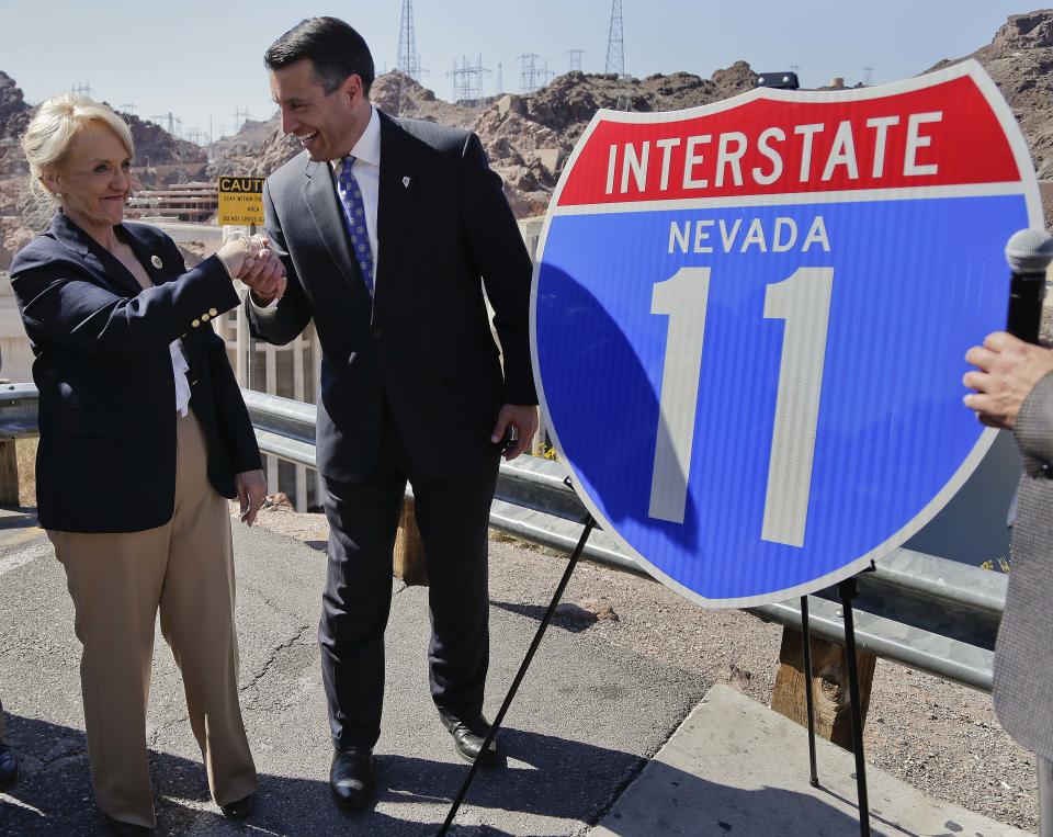 Arizona governor Jan Brewer, left, shakes hands with Nevada governor Brian Sandoval after unveiling a sign for the future Interstate 11, Friday, March 21, 2014, at Hoover Dam, Ariz. The two governors gathered to unveil signs that will be posted along the proposed Interstate 11. It was a symbolic effort meant to keep up momentum on the project, which is coming of age in an era of scarce highway funding. (AP Photo/Julie Jacobson)