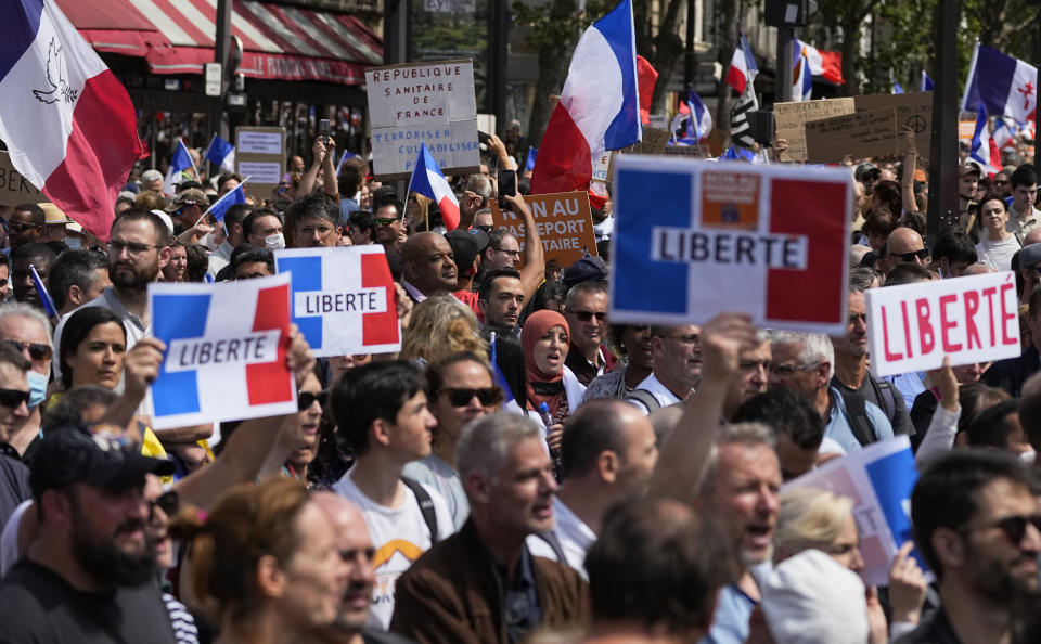 Protestors hold signs which read "freedom" during a demonstration in Paris, France, Saturday, July 31, 2021. Demonstrators gathered in several cities in France on Saturday to protest against the COVID-19 pass, which grants vaccinated individuals greater ease of access to venues. (AP Photo/Michel Euler)