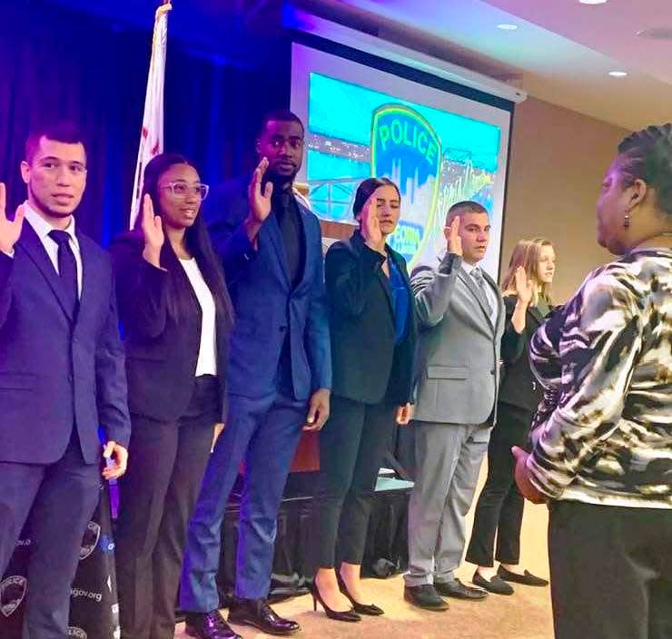 Peoria native and former Manual High School and University of Illinois basketball guard Da'Monte Williams (middle) stands tall during a swearing-in ceremony for Peoria Police officer recruits on Monday, Aug. 28, 2023, at Peoria Civic Center.