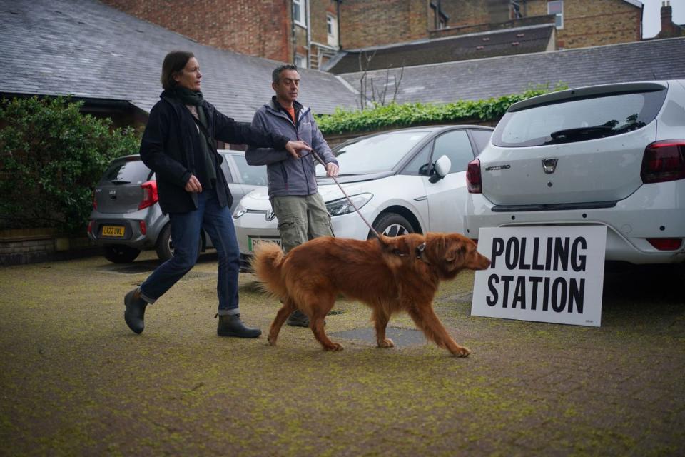 Cinna, an 8-year-old rescue dog from Greece, arrives with owners at the polling station at St Alban's Church, south London (Yui Mok/PA Wire)