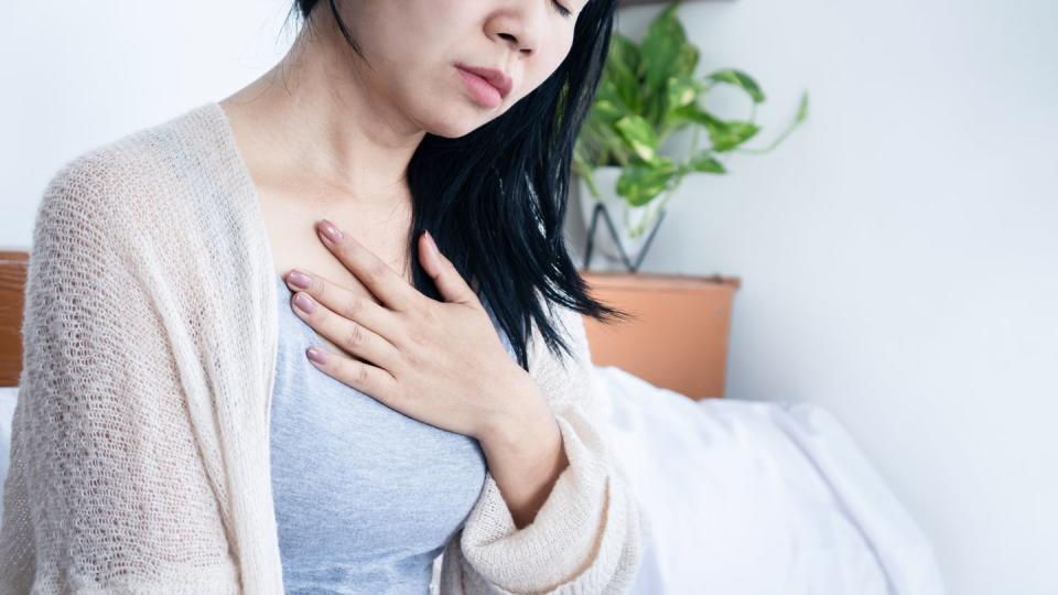 asian woman hand holding chest pain, difficulty to breathe