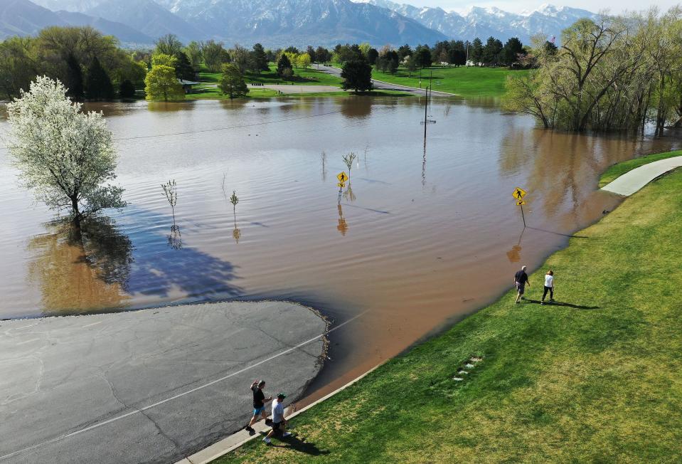 Walkers go around the flooded road where a pond has formed in Sugarhouse Park in Salt Lake City on Tuesday, May 2, 2023. | Jeffrey D. Allred, Deseret News