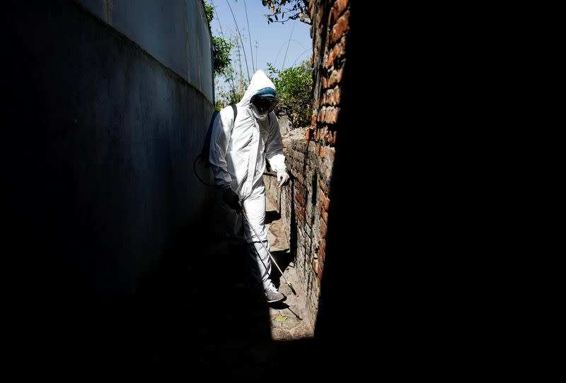 Light Illuminates a volunteer as he sprays disinfectant along the alley during the tenth day of the lockdown imposed by the government amid concerns about the spread of coronavirus disease (COVID-19) outbreak, in Kathmandu