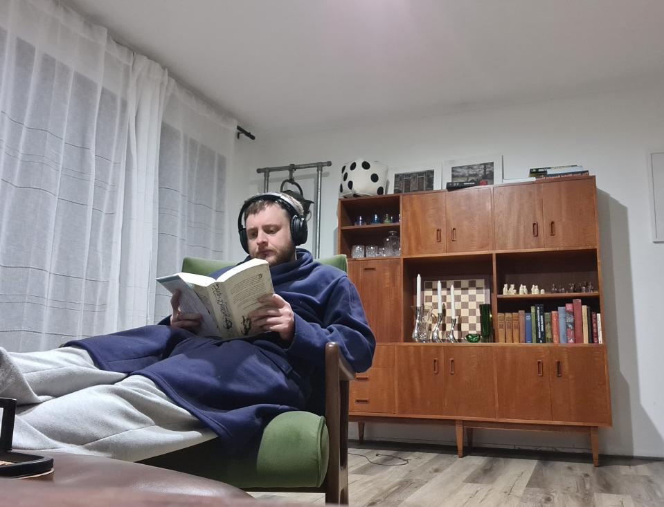 twitch exec lewis mitchell sits in chair reading while wearing bathrobe and sweats