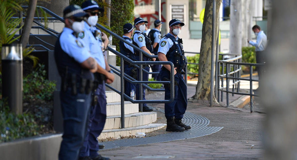A group of masked officers stand outside a police station in Sydney.