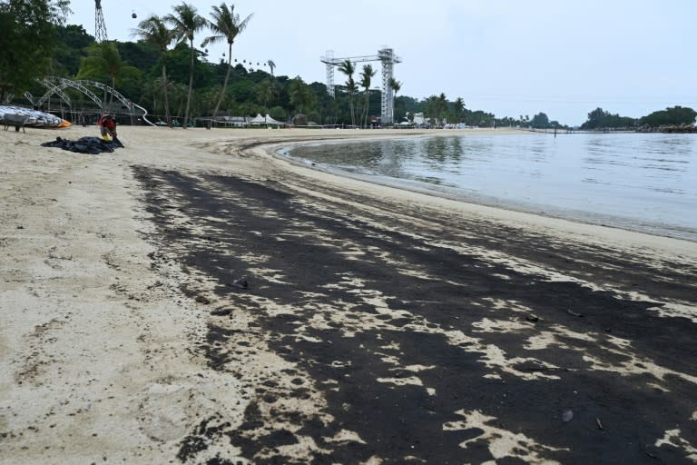 A worker clears oil slick on Sentosa island's Siloso beach in Singapore on June 15 (ROSLAN RAHMAN)