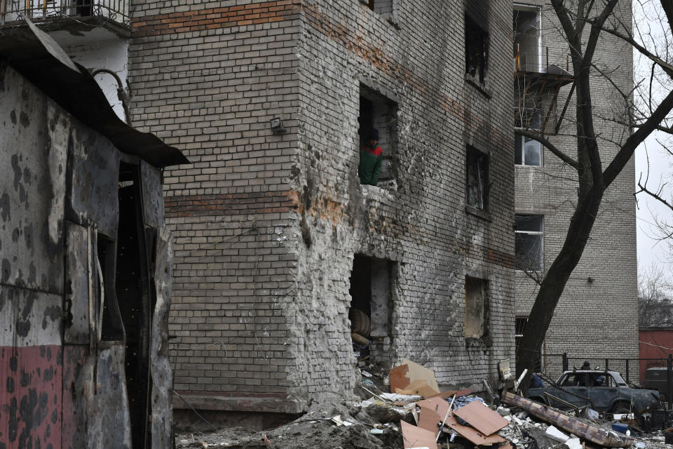 A local resident looks out of a broken window of an apartment building damaged in the night following a Russian rocket attack in Zaporizhzhya, Ukraine, Monday, Jan. 16, 2023. (AP Photo/Andriy Andriyenko)