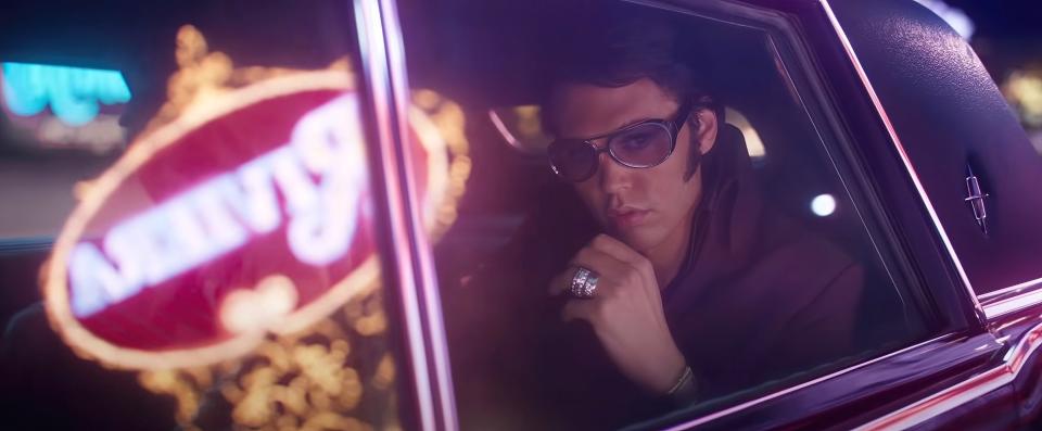 Elvis riding in a limo with las vegas lights reflecting on the windows