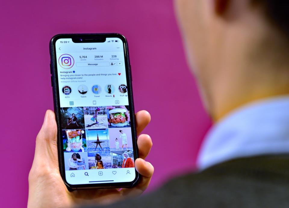 A man looking at the home page of social media site Instagram on a smartphone (PA) (PA Archive)