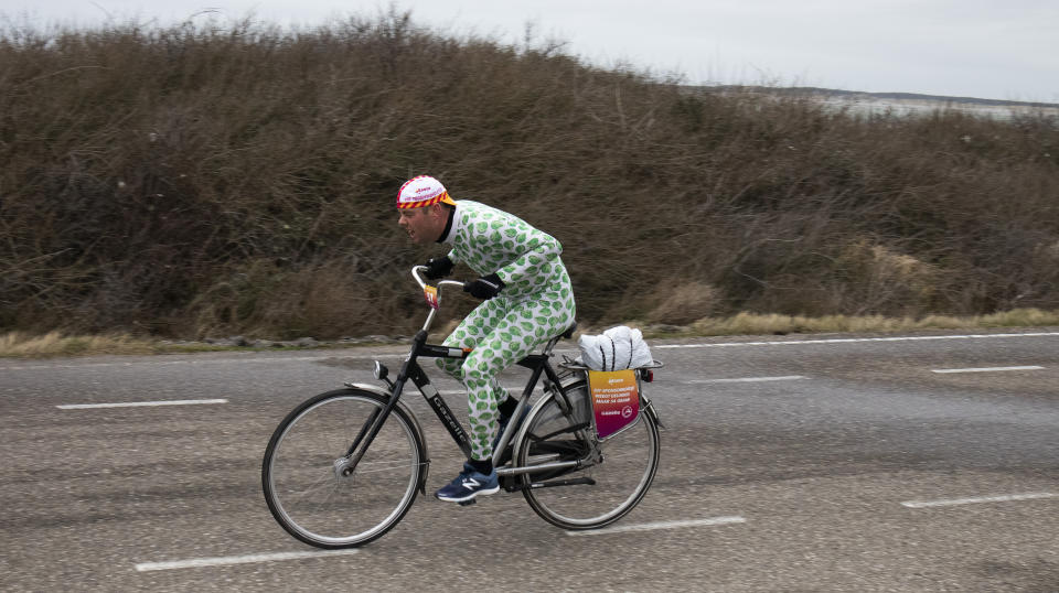 A competitor wearing a onesie with Brussels sprouts battles gale force winds during the Dutch Headwind Cycling Championships on the storm barrier Oosterscheldekering near Neeltje Jans, south-western Netherlands, Sunday, Feb. 9, 2020. (AP Photo/Peter Dejong)