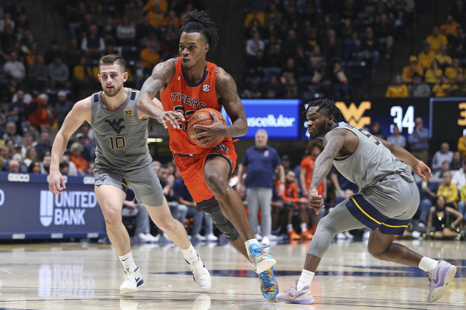 Auburn guard Allen Flanigan (22) drives between West Virginia guards Erik Stevenson (10) and Joe Toussaint (5) during the first half of an NCAA college basketball game on Saturday, Jan. 28, 2023, in Morgantown, W.Va. (AP Photo/Kathleen Batten)