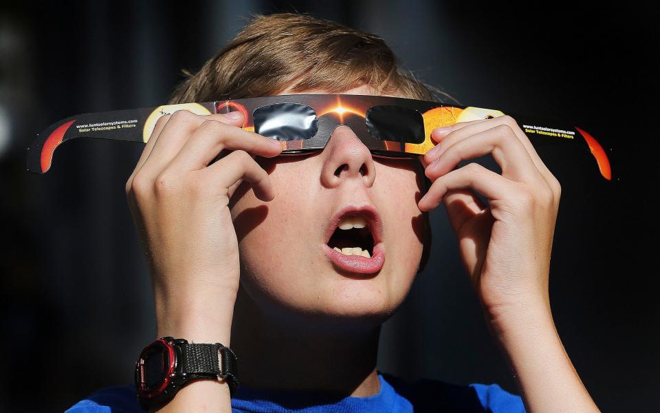 Colton Hammer tries out his new eclipse glasses he just bought from the Clark Planetarium in Salt Lake City - AP