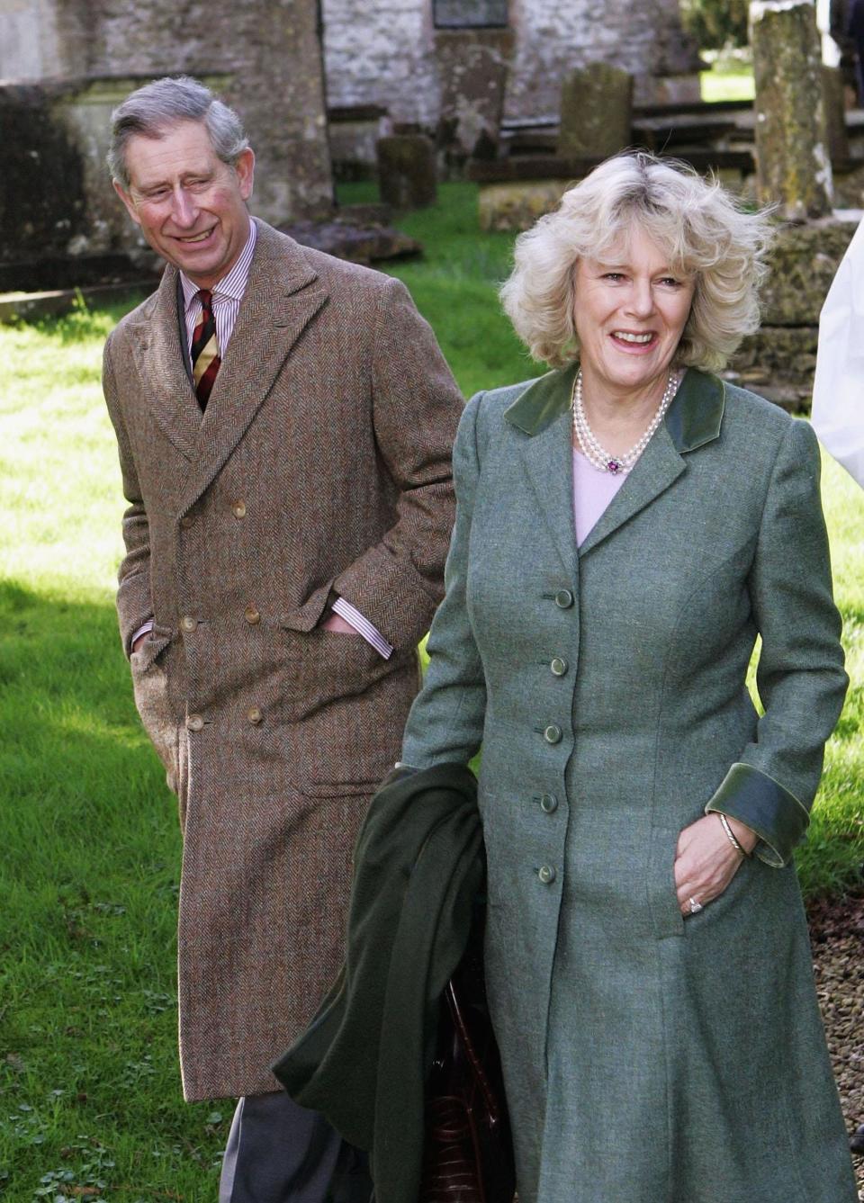 King Charles III and Camilla, Queen Consort walk through a field.