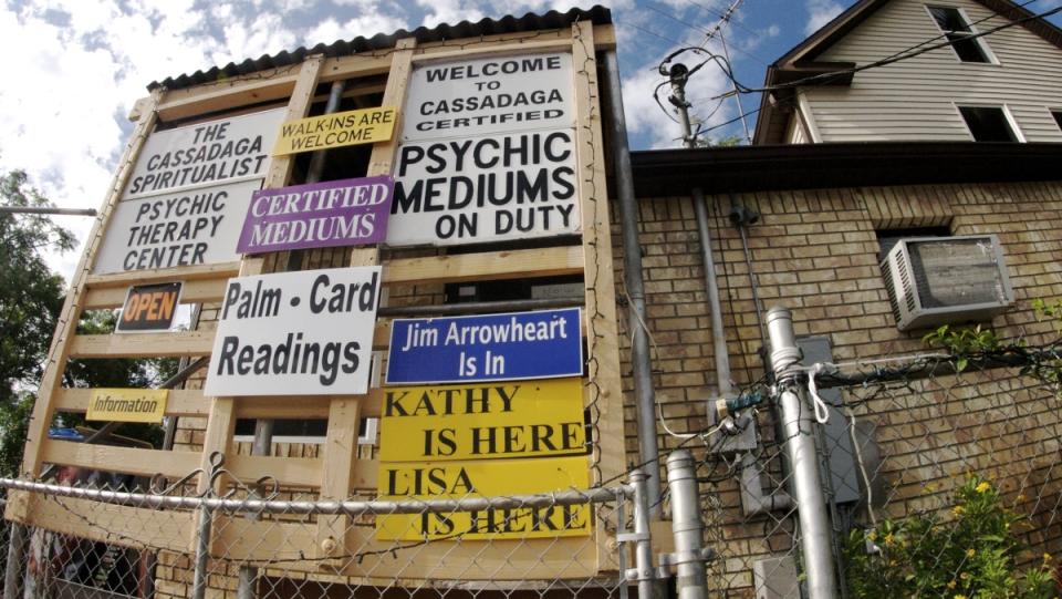 a side of a run down building with several signs advertising psychic mediums