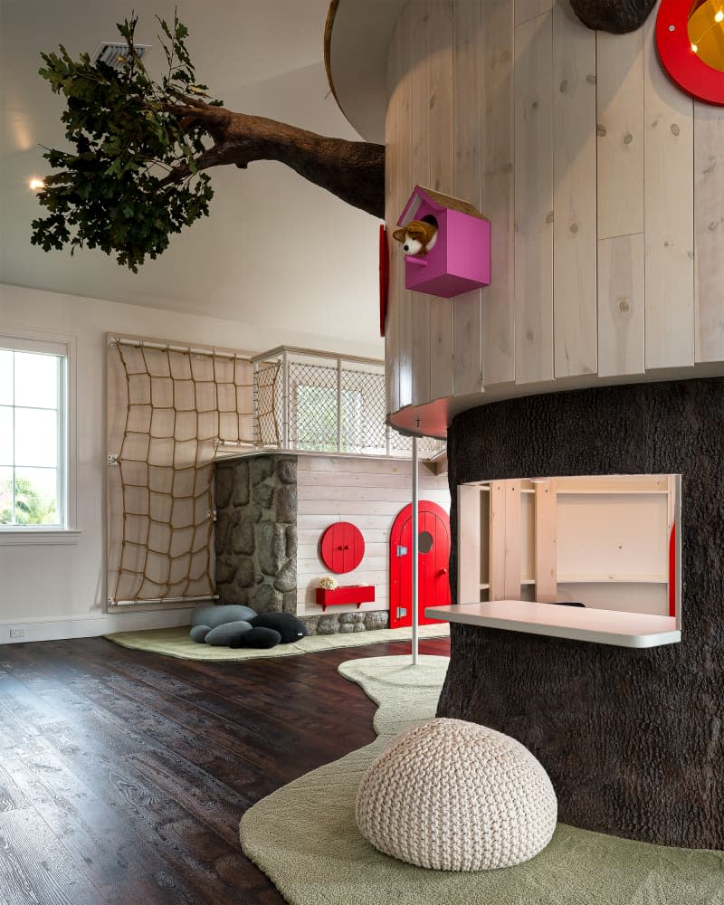 Faux tree house in child's playroom with red door in background.