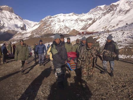 Nepalese army personnel carry a victim rescued from the avalanche at Thorang-La in Annapurna Region in this October 15, 2014 handout photo provided by Nepal Army. REUTERS/Nepal Army/ Handout via Reuters