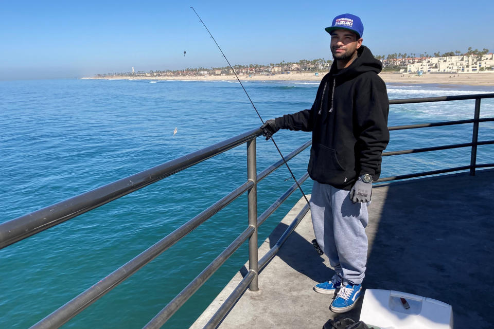 Michael Archouletta, 29, said he came down to Huntington Beach from East Los Angeles early to fish and didn't see any signs barring him from fishing on the pier in Huntington Beach, Calif., Sunday, Oct. 10, 2021. Fishing has been closed along the shore since an offshore pipeline was found leaking oil into the Pacific Ocean waters off the coast of Orange County. (AP Photo/Amy Taxin)