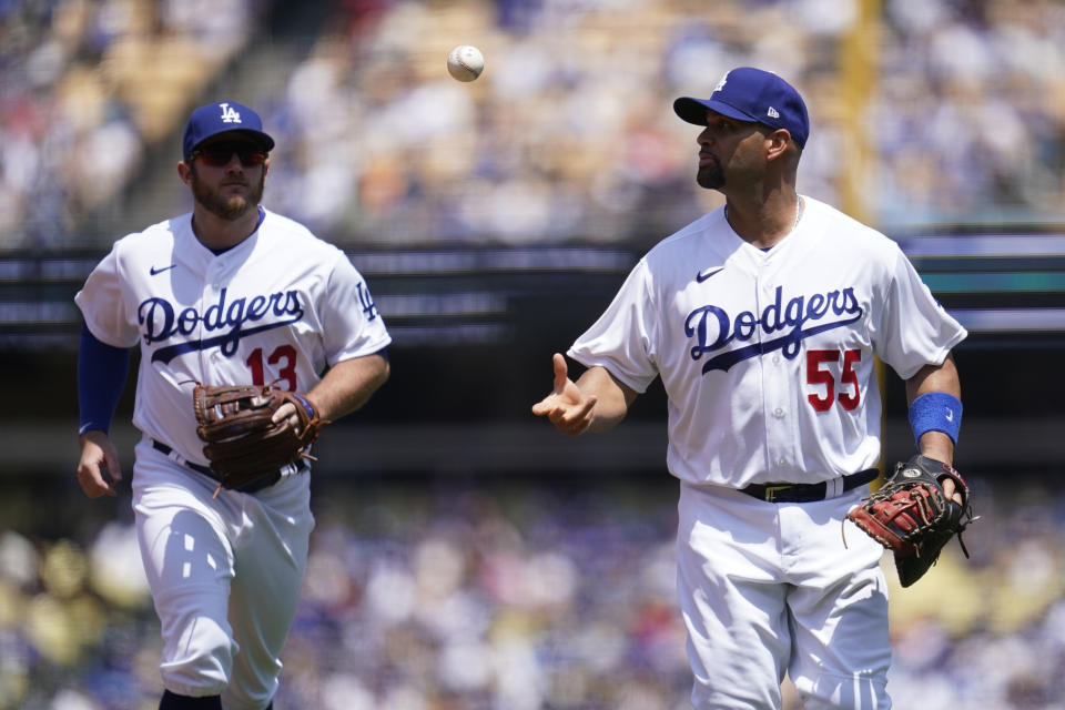 Los Angeles Dodgers first baseman Albert Pujols (55) tosses a ball to second baseman Max Muncy (13) as they run to the dugout in the middle of the third inning of a baseball game against the San Francisco Giants Sunday, May 30, 2021, in Los Angeles. (AP Photo/Ashley Landis)