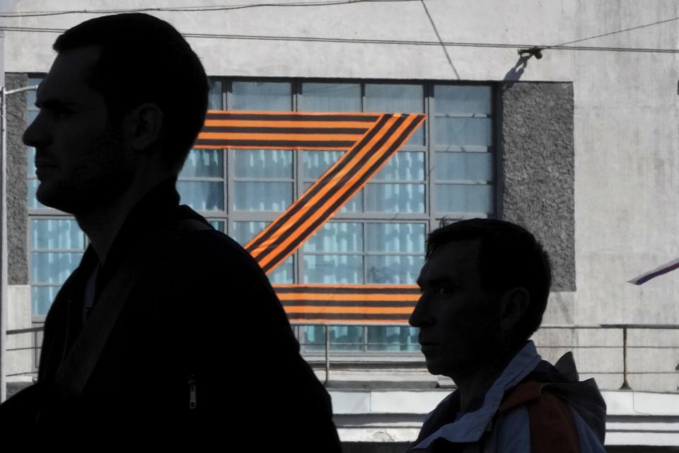 People walk past a letter Z, which has become a symbol of the Russian military, displayed on a building in St. Petersburg, Russia, Friday, May 6, 2022. (AP Photo/Dmitri Lovetsky)