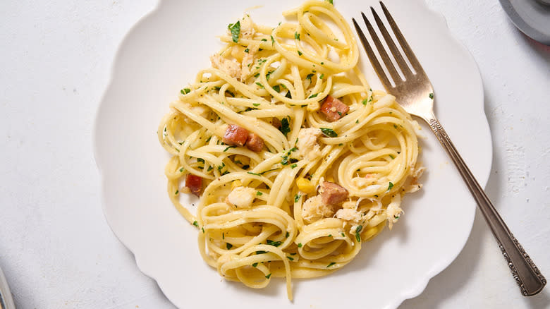 crab and sausage carbonara pasta served on white plate