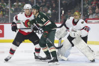 Ottawa Senators defenseman Jakob Chychrun, left, and Minnesota Wild center Joel Eriksson Ek (14) compete for position as goaltender Joonas Korpisalo defends his net during the first period of an NHL hockey game Tuesday, April 2, 2024, in St. Paul, Minn. (AP Photo/Matt Krohn)