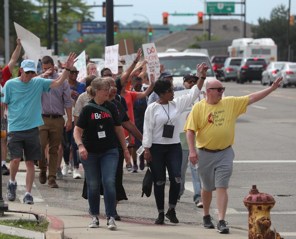 The Rev. Ron Shultz of Family of Faith Methodist Church in Akron, right, waves to cars that honk support during the Walk for Our Lives walk against gun violence.