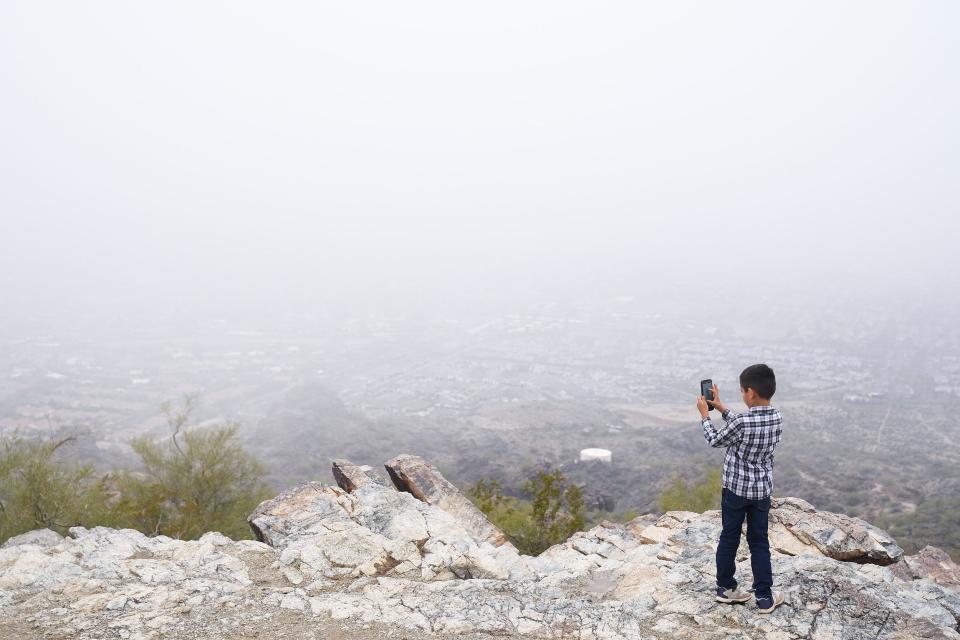 Saul Ruiz, 7, takes a video of the view at Dobbins Lookout on an overcast day on Dec. 4, 2022, in Phoenix.