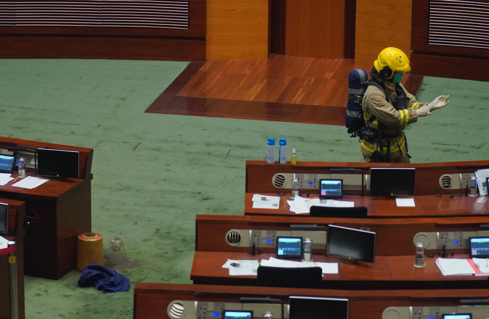 A firefighter checks the main chamber of the Legislative Council after a pro-democracy lawmaker dropping a pot of a pungent liquid in the chamber in Hong Kong, Thursday, June 4, 2020. A Hong Kong legislative debate was suspended Thursday afternoon ahead of an expected vote on a contentious national anthem bill after pro-democracy lawmakers staged a protest. (AP Photo/Vincent Yu)