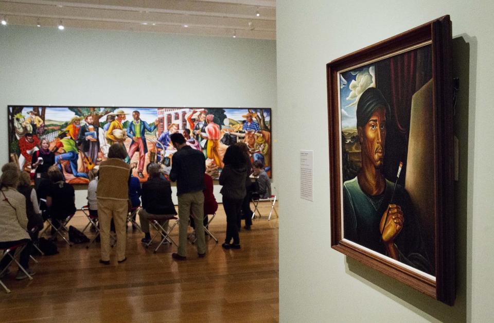 In this Monday, Feb. 6, 2017 photo, Frederick C. Flemister's painting "Man with Brush" from 1940 hangs at right as docents are given a tour of the exhibit "Cross Country: The Power of Place in American Art, 1915-1950," at the High Museum of Art in Atlanta. The new exhibition at takes a look at how American artists during the modernist period traveled outside cities to find inspiration in the rural landscape. (AP Photo/David Goldman)